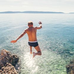 Man jumps in blue sea lagoon water